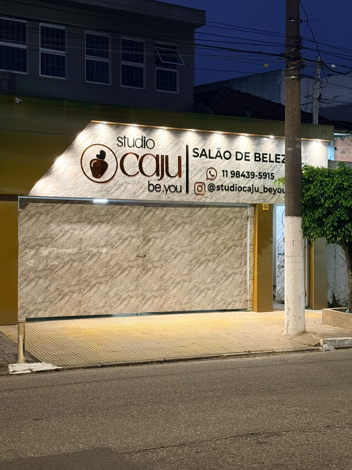 Fachada do Studio Caju iluminada à noite.